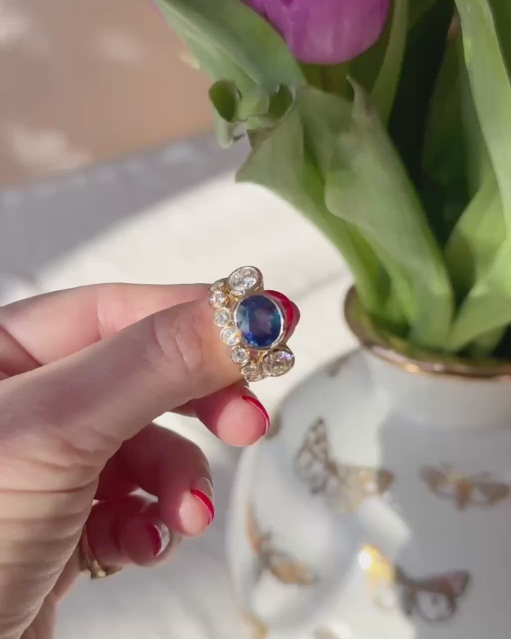 A hand holding and turning a sapphire and diamond ring 